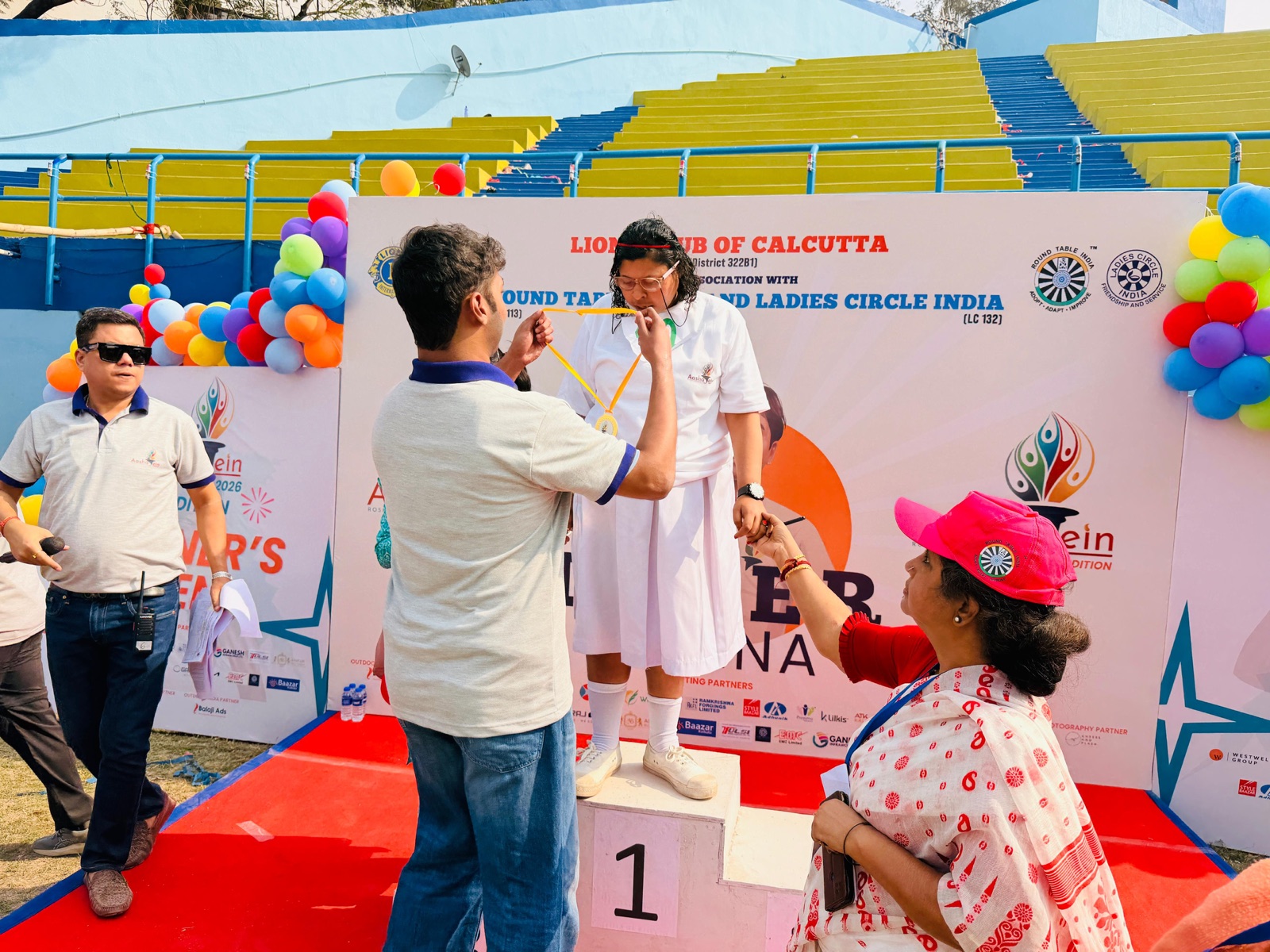 On the podium at Aashayein 2026 with a young athlete